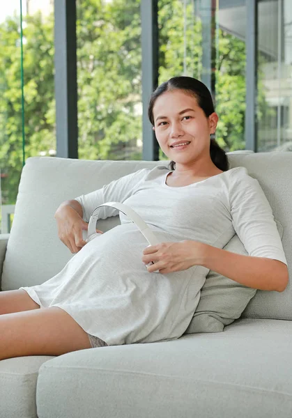 Mulher Grávida Está Sentada Sofá Ouvindo Música Fones Ouvido Smartphone — Fotografia de Stock