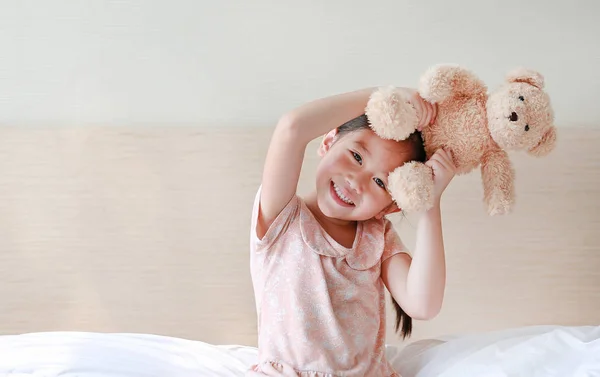 Счастливая Азиатская Девочка Показывает Плюшевых Мишек Сидя Дома Кровати — стоковое фото