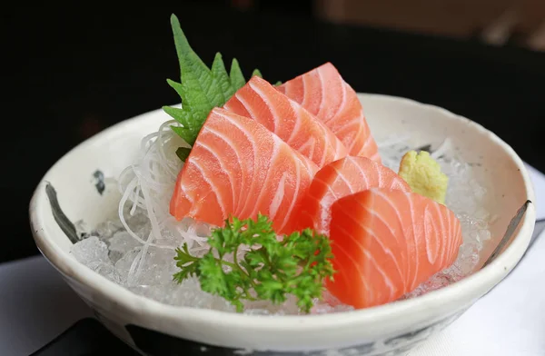 stock image Salmon raw slice or salmon sashimi in Japanese style fresh serve on ice with fresh wasabi on black table