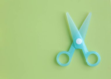 Yeşil arka plan için mavi plastik çocuk Emanet makaslar.