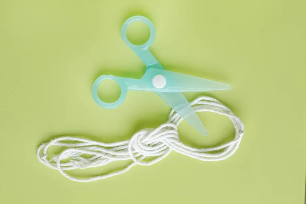 绿色塑料儿童安全剪刀 带绳子的绿背景 — 图库照片