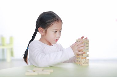 Küçük şirin Asyalı kız çocuğu sınıfta Beyin ve Fiziksel Gelişim için ağaç blokları kule oyunu oynuyor. Çocukların yüzüne odaklan. Çocuk hayal gücü ve öğrenme kavramı.