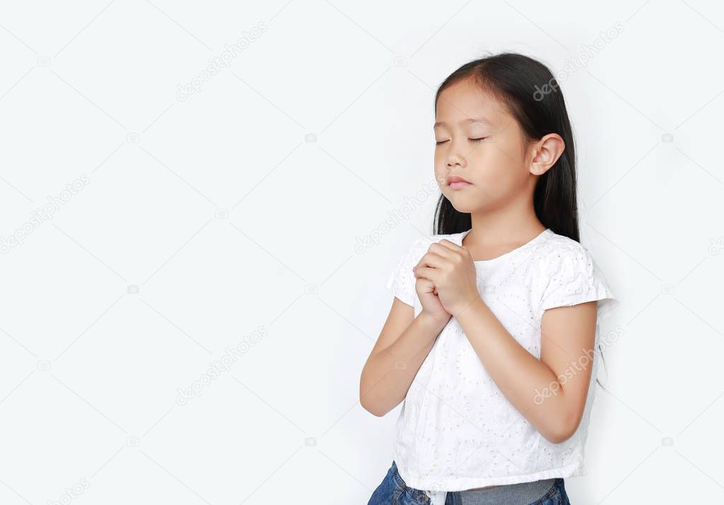 Close eyes beautiful little asian child girl praying isolated on white background with copy space. Spirituality and religion concept.