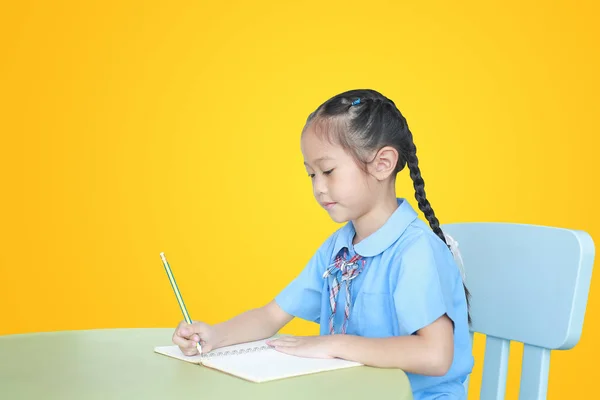 Ασιατικό Κοριτσάκι Σχολική Στολή Γράφει Στο Σημειωματάριο Στο Γραφείο Απομονωμένο — Φωτογραφία Αρχείου