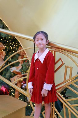 Kırmızı elbiseli güzel Asyalı kız kış mevsiminde poz veriyor ve yılbaşı arkaplanına karşı yeni yıl festivaliniz kutlu olsun..