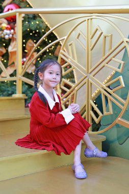 Kırmızı elbiseli güzel Asyalı kız kış mevsiminde poz veriyor ve yılbaşı arkaplanına karşı yeni yıl festivaliniz kutlu olsun..