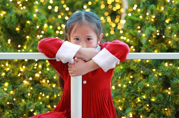 穿着红色衣服的小女孩挂在篱笆上的画像 在圣诞节的背景下欢度新年 — 图库照片