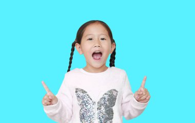 Neşeli küçük Asyalı kız iki parmağını kaldırdı. Cyan arka planında izole edilmiş tezahürat yapmak için. Neşeli duygu konsepti.