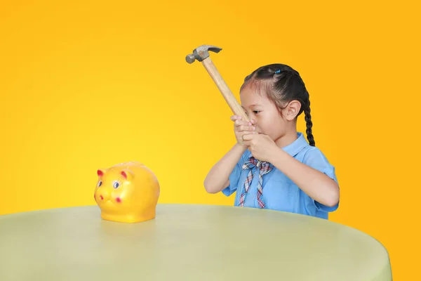 Mała Dziewczynka Szkolnym Mundurku Próbuje Złamać Świnkę Żółtym Tle Przy — Zdjęcie stockowe