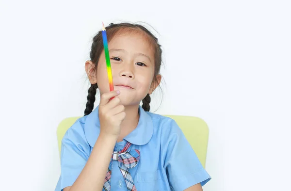 笑顔アジアの女の子で学校制服保持色鉛筆と見ますカメラ上の白い背景フォーカス上の顔 — ストック写真