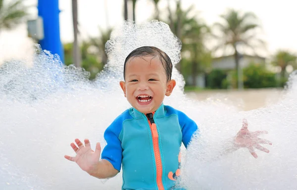 在户外的泡沫派对上 快乐的亚洲小男孩笑着玩乐的画像 图库照片