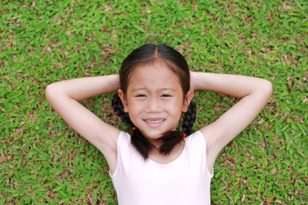 Улыбающаяся Маленькая Азиатская Девочка Двумя Хвостиками Лежащими Зеленой Траве Саду — стоковое фото