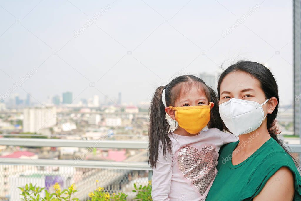 Mother carrying her daughter with wearing a protection mask against PM 2.5 air pollution in Bangkok city. Thailand.