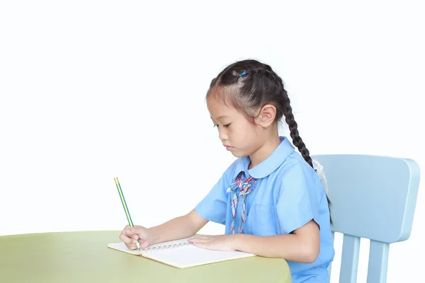 意図する小さな子供女の子で学校制服書き込みノートブック上のデスク隔離されました上のホワイトバックグランド — ストック写真