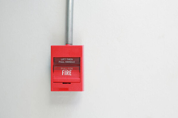 Fire alarm switch on white cement wall.