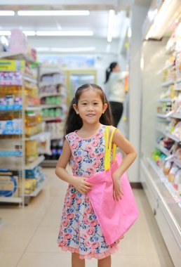 Happy girl shopping in department store with carrying a pink recycle bag (spun ball bag). Eco friendly bag for reduce or zero waste concept