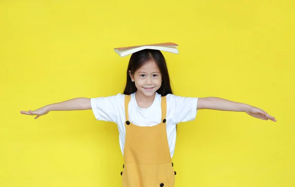 Азиатская Девочка Книгой Голове Изолирована Желтом Фоне Портрет Счастливой Школьницы — стоковое фото