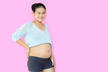 Mutlu Asyalı hamile kadının portresi pembe arka planda fotokopi alanı ile poz veriyor..