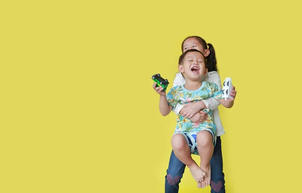 Brincalhão Feliz Asiático Irmã Abraçando Levantar Seu Irmãozinho Fundo Amarelo — Fotografia de Stock