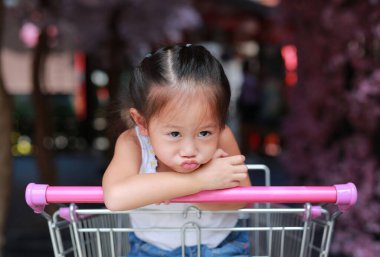 Aile içinde belgili tanımlık çarşı alışveriş sırasında arabası içinde oturan sıkılmış Asyalı küçük kız çocuk.