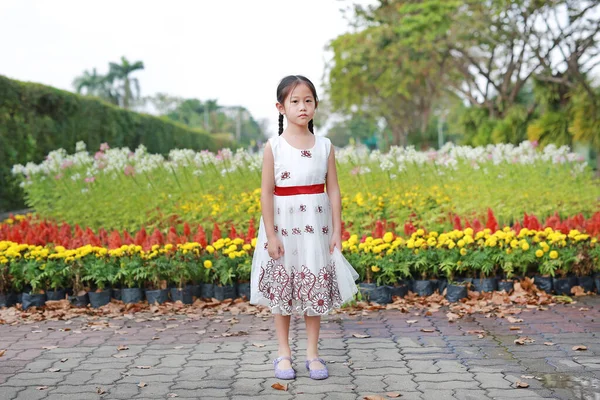 平和的なアジアの小さな子供の女の子は午前中に新鮮な花の庭に立っている — ストック写真