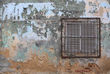 Paslı demir parmaklıkları olan eski bir binanın havalandırması.