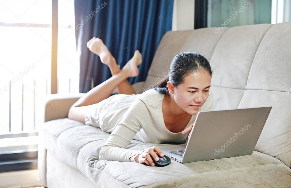 Asian woman using laptop computer working online at home and feel relaxing. People during the introvert time at home from the epidemic