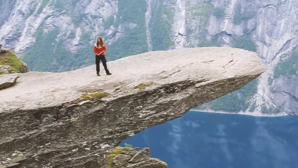 Odda, Norsko. Mladá dívka žena dělá gymnastické cvičení stojící na skále. People Are Photographed Standing On A Rock Trollunga - Troll Language In Norway. — Stock video