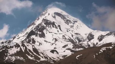 Kazbegi, Georgia. Kazbek Dağı 'nın zirvesi karla kaplı. Kazbek bir Stratovolcano ve Gürcistan Kazbegi ve Rusya sınırında yer alan Kafkasya 'nın en büyük dağlarından biridir..