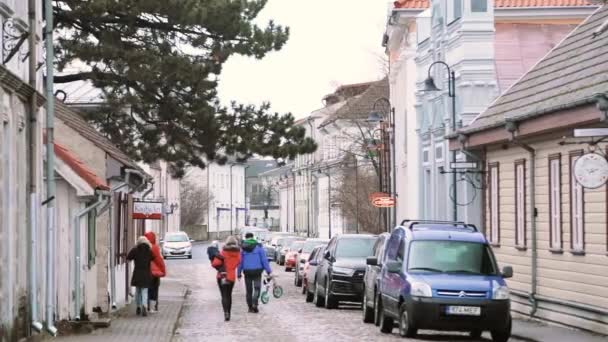 Kuressaare, Isla Saaremaa, Estonia. Personas Familia caminando en la calle Kauba en el día nublado de invierno. Casas tradicionales antiguas en calles estrechas — Vídeos de Stock