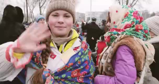 Гомель, Білорусь. Дівчинка в Національному народному Хедшарфі розмахує рукою до камери під час святкування Слов'янського національного традиційного свята Масленіца. Зимові весняні свята — стокове відео