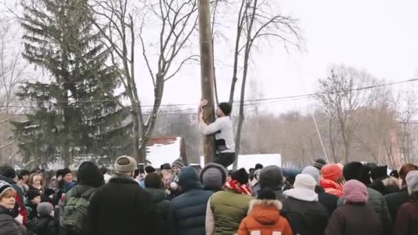 Гомель, Білорусь. Молодий чоловік піднімається на дерев'яну пошту На традиційне свято, присвячене наближенню весняного - слов'янського святкування Шроветіда. Національне традиційне свято Масленіца — стокове відео