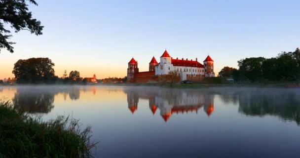 Mir, Bělorusko. Mir Castle Complex From Side Of Lake. Architektonický soubor feudalismu, starobylá kulturní památka, památka světového dědictví UNESCO. Slavná památka. Mlha nad jezerem v letním ránu — Stock video