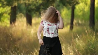 Beyaz tişörtlü, gülen, gülen, beyaz tişörtlü, yaz yeşil ormanında dans eden bekar, genç ve güzel beyaz bir kadın. Açık hava yaz doğasının tadını çıkarın. Ağır çekim, ağır çekim, ağır çekim, ağır çekim.