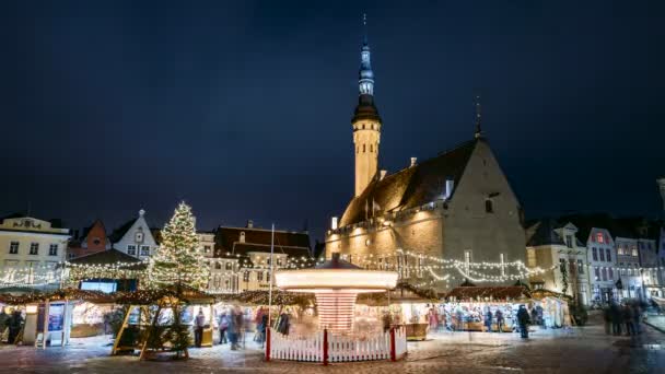 エストニアのタリン。町役場広場で伝統的なクリスマスマーケットやカルーセルのタイムラプス。クリスマスツリーと商社。有名なランドマークとユネスコ世界遺産 — ストック動画