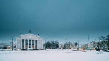 Gomel, Belarus. Gündüzden geceye hızlandırılmış zaman geçişi. Kış mevsiminde Lenin Meydanı 'ndaki Gomel Tiyatrosu' nun yakınındaki trafik ve aydınlık patikalar. Günün Geceye Dönüşümü