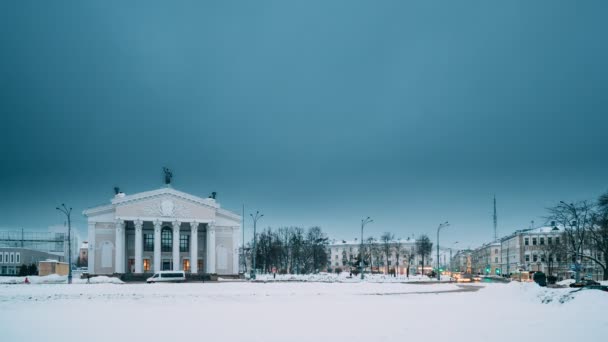 Гомель, Білорусь. Час минає від дня до ночі. Трафік і легкі стежки біля будівлі Гомельського обласного драматичного театру На площі Леніна в зимовий сезон. Зміна дня на ніч — стокове відео