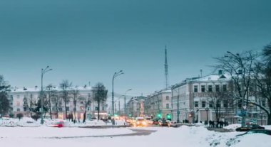 Gomel, Belarus. Gündüzden geceye hızlandırılmış zaman geçişi. Kış mevsiminde Lenin Meydanı 'ndaki Gomel Tiyatrosu' nun yakınındaki trafik ve aydınlık patikalar. Günün Geceye Dönüşümü