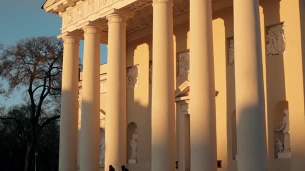 Vilnius, Lituânia. Pessoas caminhando na Praça da Catedral perto da Basílica da Catedral de St. Stanislaus e St. Vladislav com a torre do sino na primavera à noite — Vídeo de Stock