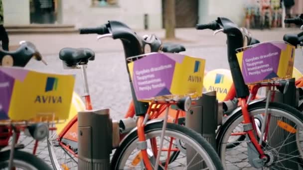 Wilno, Litwa. Wiersz kolorowych rowerów AVIVA do wynajęcia na miejskim parkingu rowerowym na ulicy. — Wideo stockowe