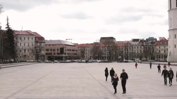 Vilnius, Litva. Lidé kráčející v katedrále náměstí v blízkosti katedrály baziliky sv. Stanislava a sv. Vladislava s zvonicí na jaře Evropy — Stock video