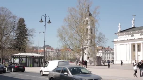 Vilnius, Litva. Lidé kráčející v katedrále náměstí v blízkosti katedrály baziliky sv. Stanislava a sv. Vladislava s zvonicí na jaře Evropy — Stock video