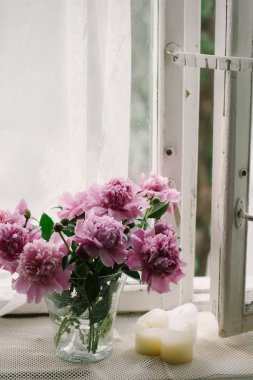 Eski bir pencere eşiğinde bir vazoda pembe peonies