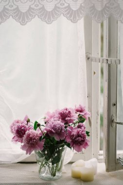 Eski bir pencere eşiğinde bir vazoda pembe peonies