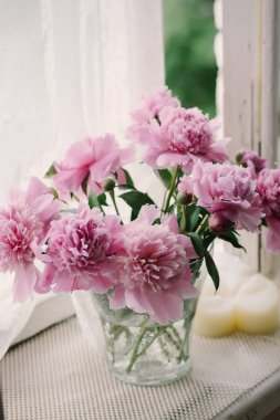Eski bir pencere eşiğinde bir vazoda pembe peonies