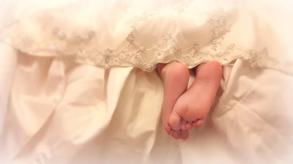 Baby legs from under the lace dress. — Stock Photo, Image