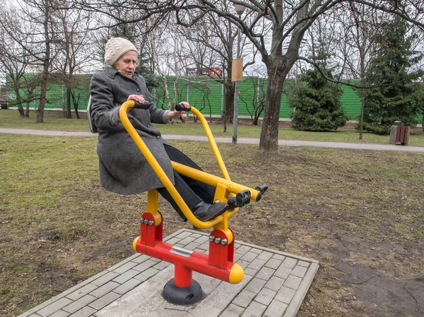 Mujer mayor practicando en equipo de gimnasio en el parque —  Fotos de Stock