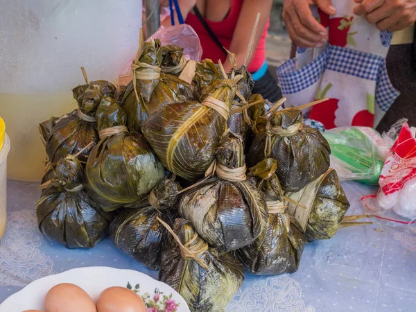 Meat and rise wraped in palm leaves — Stock Photo, Image