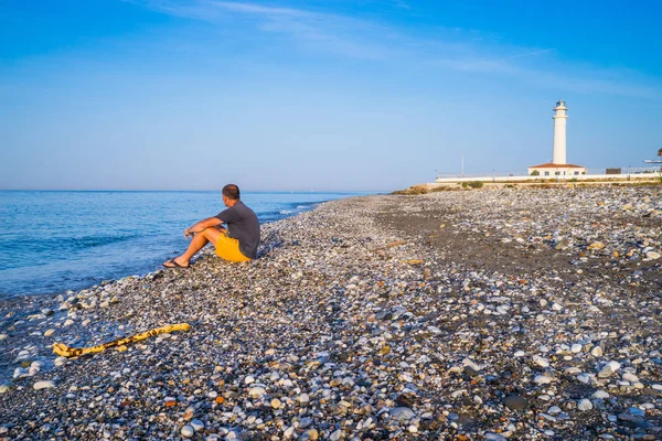 Самотній чоловік на пляжі з маяком Стокове Фото