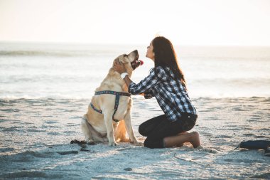 Kumsalda köpekle oynayan kız